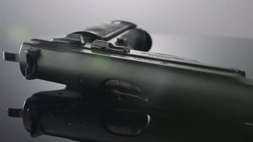 Waffenkontrolle. Studioaufnahme einer 9-mm-Pistole, die sich auf einer reflektierenden Oberfläche dreht