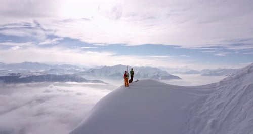 Aerial drone view of two mountain climbers on top of a snow covered mountain