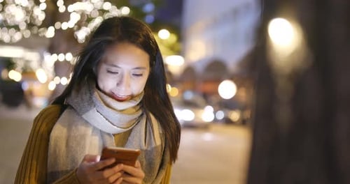 Woman look at mobile phone in city at night