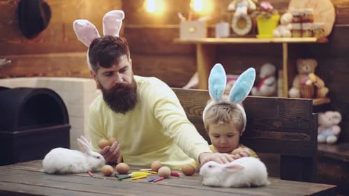 Father and Son Preparing Easter Eggs with Rabbits