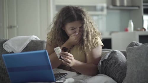 Young Woman with Cold Examines Medicine at Home