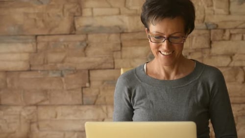 Smiling Woman Working on Laptop at Home