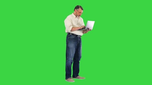Handsome Senior Man Using Laptop and Celebrating Victory on a Green Screen Chroma Key