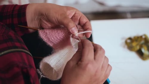 Hands Knitting Pink and White Yarn Close Up