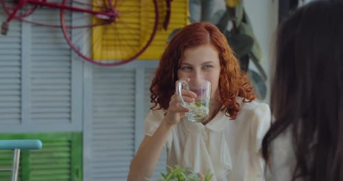 Zwei Kolleginnen trinken Tee, reden und lachen in der Mittagspause.