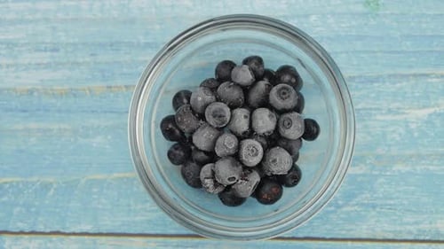 Bowl of frozen blueberries sitting on blue wood