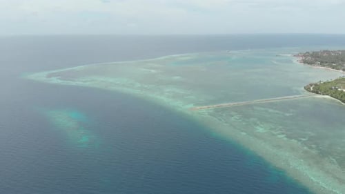 Aerial: Flying over coral reef turquoise water tropical island, scenic travel