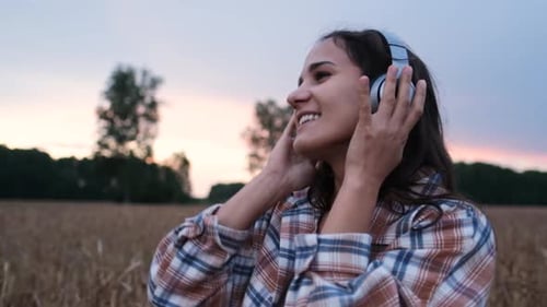 Smiling Woman Dances in Wheat Field at Sunset