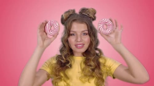 Woman Holds Donuts Over Eyes and Smiles