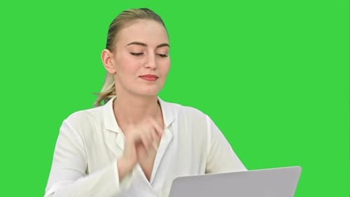 Pretty Young Business Woman Positively Working on a Laptop on a Green Screen, Chroma Key.