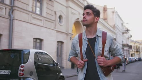 Attractive Young Handsome Man Tourist with Backpack Walking in City Center and Looking Around