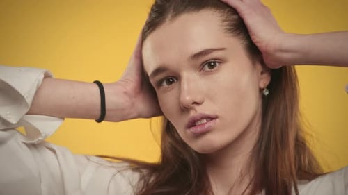 Young Adult Caucasian Woman is Posing on a Bright Yellow Background in Studio