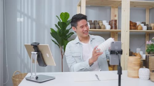 Asian young handsome man sell vase product online live streaming at home.