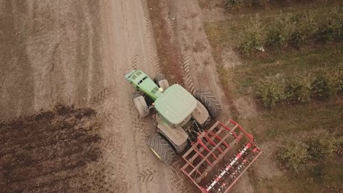 a Large Tractor Plows a Field