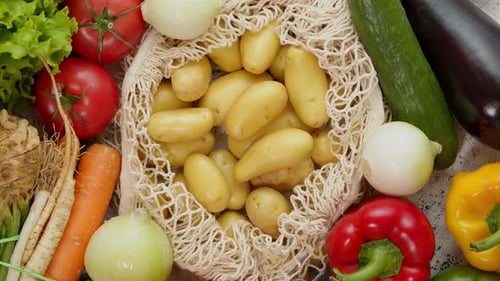 Verduras en bolsas de red reutilizables sobre fondo blanco rayado: vista superior