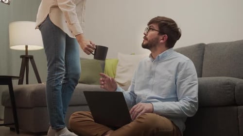 Man Working on Laptop Receives Coffee at Home