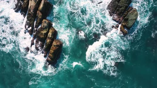 Las olas azules del océano rompen en el alto acantilado de una montaña rocosa. Peligro: olas marinas en un