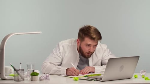 Young Student Doing Study Assignments on His Computer While Sitting at Laptop in Home Office