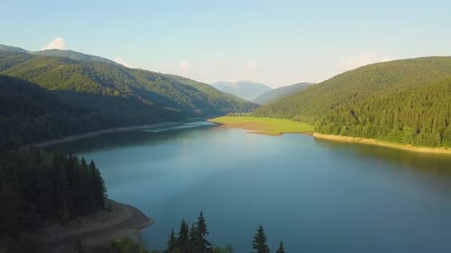 Aerial view of big lake with clear blue water between high mountain hills covered with
