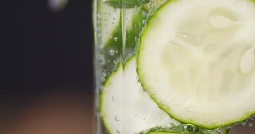 Tranches rondes de concombre sous l'eau avec des bulles d'air.