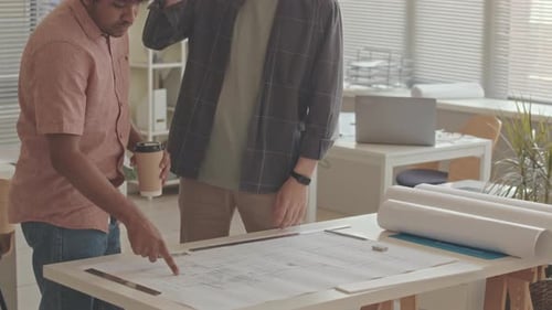 Team of Architects Discussing Plan of Building in Office