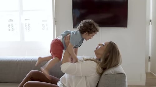 Mother Lifts Child Up in the Air Indoors