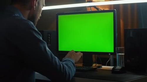 A Man Works in Front of a Computer with a Green Screen