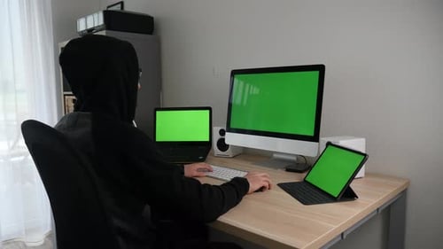 Hacker programmer working tirelessly on green screens