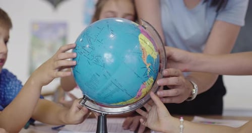 Female Teacher with Kids in Geography Class Looking at Globe