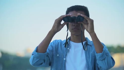 Young Man Looking Through Binoculars in City