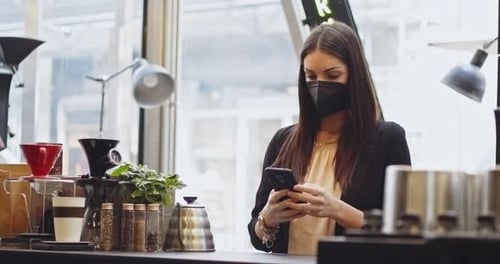 Kundenfrau in medizinischer Schutzmaske Bezahlen mit NFC-Technologie mit Telefon und Kreditkarte