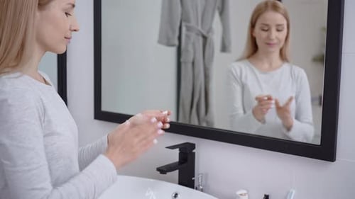 Cheerful Blonde Using Face Lotion