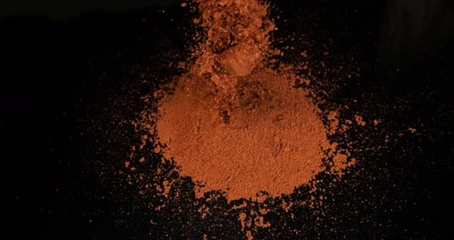Red Powder Falling Onto Black Surface Close Up