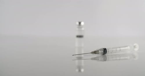 Syringe with needle and bottle close up