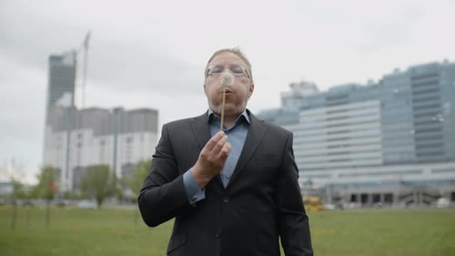 Funny Plump Man in Suit and Glasses Blows on Dandelion Outside the Office, Adult Manager in Street