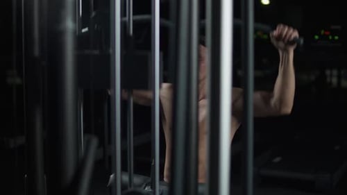 Athletic Man in the Gym Lifting Blocks on Rack Machine Training on Block Device and Gym Equipment