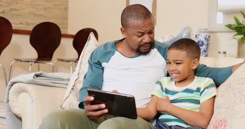 Father and Son Using Tablet on Sofa