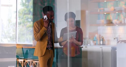 Man Talking on Phone With Woman Using Tablet