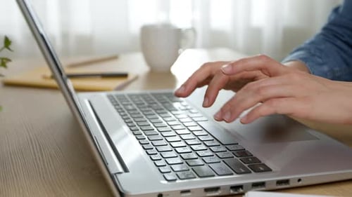 Hands of a business woman typing on a laptop keyboard while working in the office.