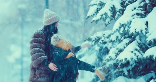 Woman and Child Play in Winter Snowfall