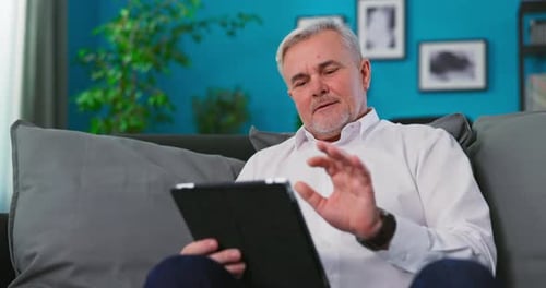 Senior Man Relaxing on Couch Using Tablet