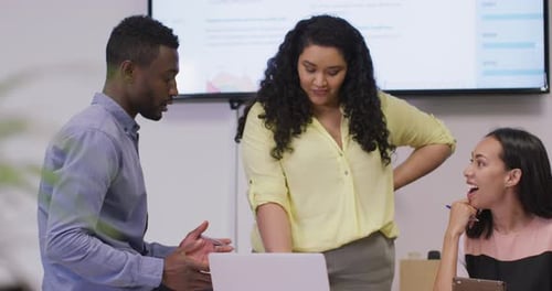 Happy diverse group of business people working together, using laptop in modern office