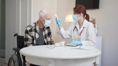 A Doctor Measures the Temperature of an Elderly Disabled Person Using an Electronic Thermometer