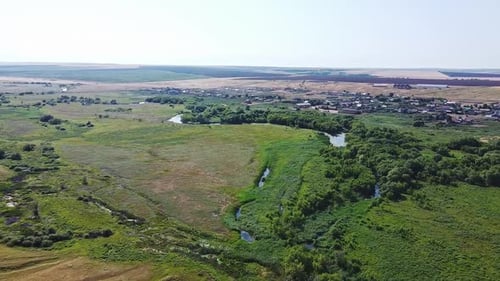 The Drone Flies Over the Countryside. Trees Grows Below and the River Glistens.