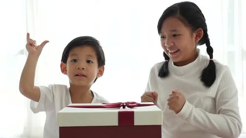 Excited Boy and Girl Opening a Present Together