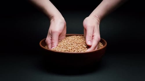 Taking Buckwheat in Hands From Bowl on Black Background