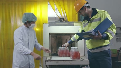 Superviseur masculin asiatique inspectant une chaîne de production de bouteilles de boissons aux herbes