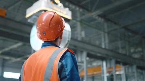 Un grutier en activité est engagé dans le chargement de produits métalliques laminés dans une entreprise ou un entrepôt