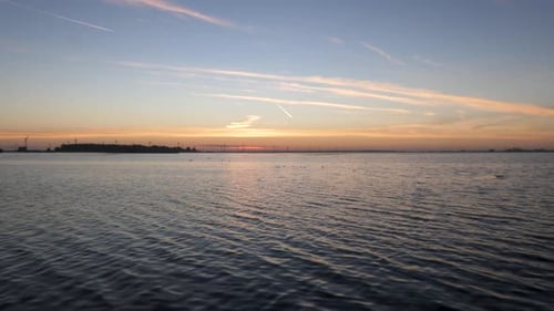 Overview of a lake at sunrise. There is a light breeze causing a nice wavy effect in the water. In t
