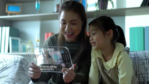 Mother and Daughter Interact with Futuristic Tablet at Home